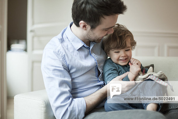 Father and young son playing on couch