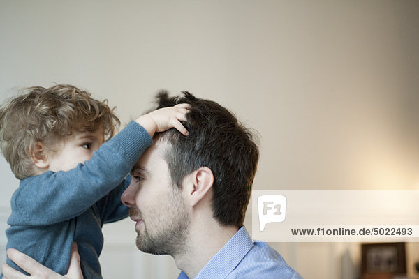 Toddler boy playing with father's hair