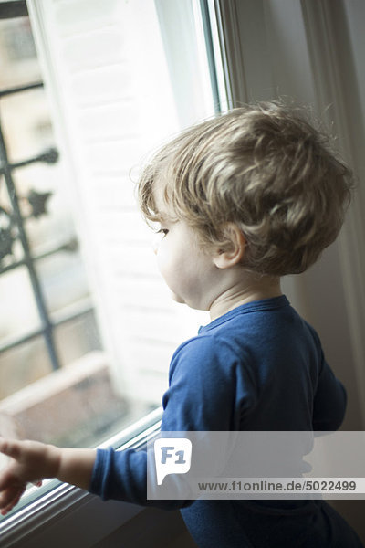 Toddler boy looking out window