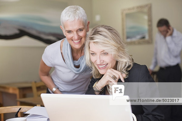 Businesswomen using laptop together