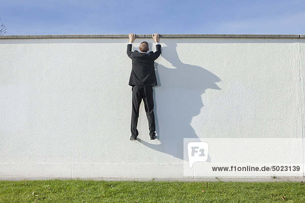 Businessman climbing over wall