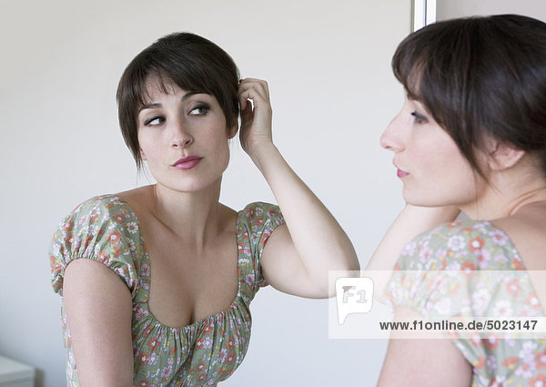 Frau untersucht Haare im Spiegel