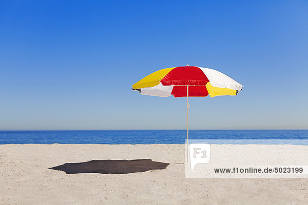 Regenschirm im Sand am leeren Strand