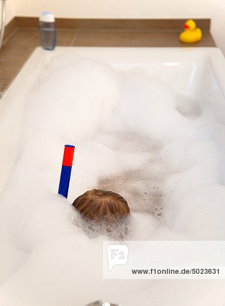 Boy wearing snorkel in bathtub