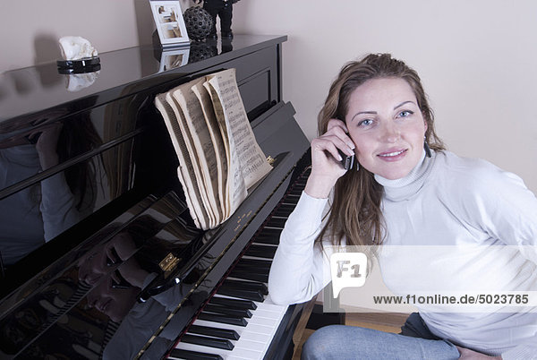 Woman talking on phone by piano