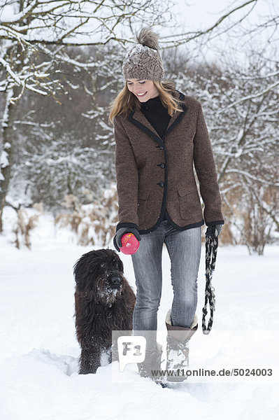 Frau Spaziergang Hund im Schnee