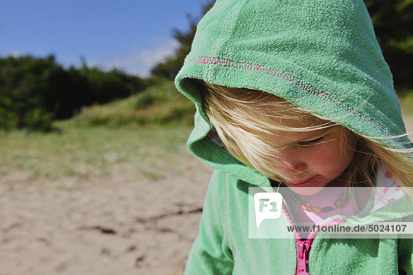 Mädchen mit Pullover am windigen Strand