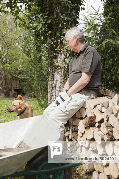 Älterer Mann ruht mit Hund im Hinterhof