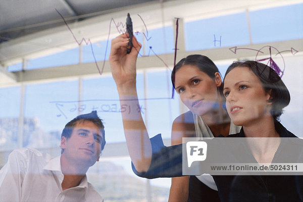 Businesswoman drawing graphs on glass
