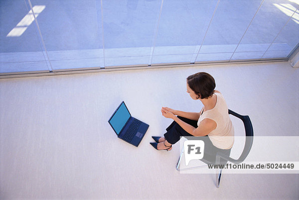 Businesswoman using laptop on floor
