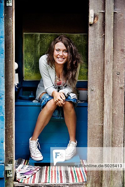 Smiling woman sitting inside outhouse