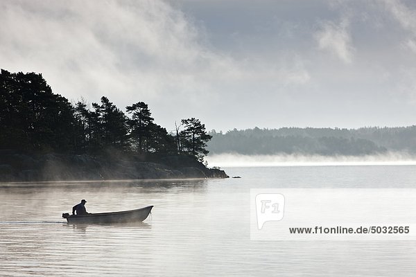 Fisherman rowing boat on lake