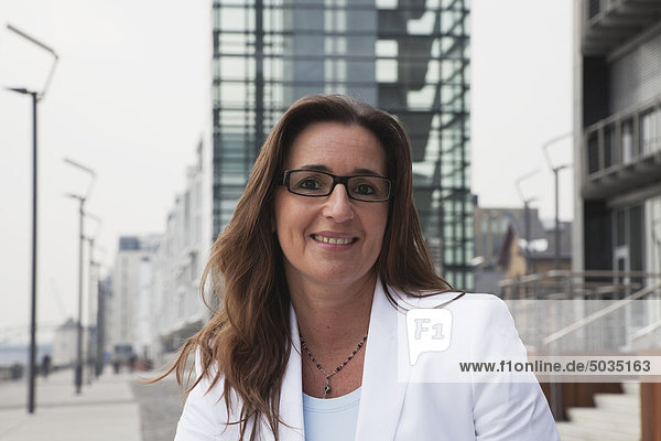 Geschäftsfrau mit Brille am Rhein und Kranhaus im Hintergrund  lächelnd  Portrait