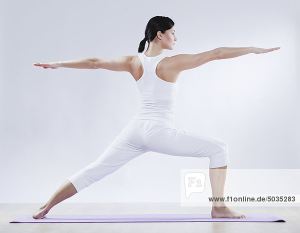 Mittlere erwachsene Frau beim Yoga vor weißem Hintergrund