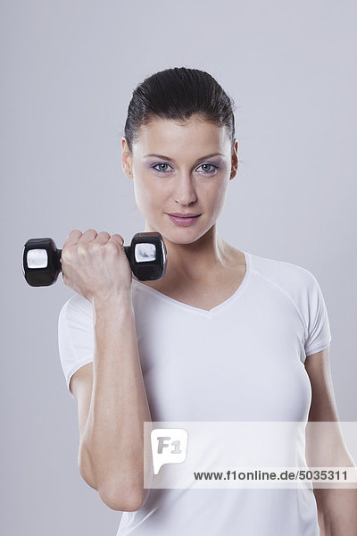Mid adult woman with barbells against white background  smiling  portrait