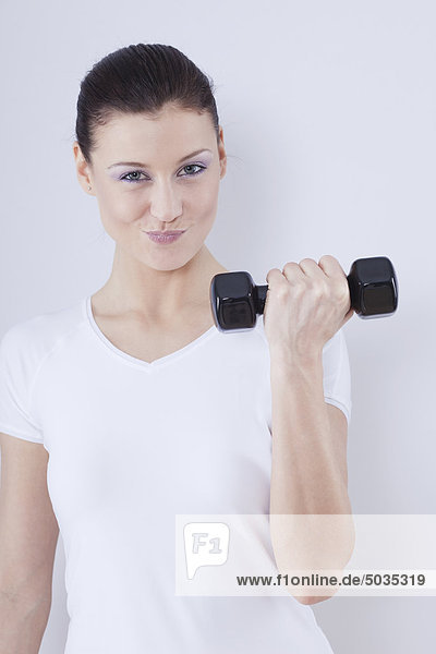 Close up of mid adult woman with barbells against white background  smiling  portrait