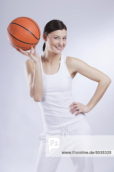 Mittlere erwachsene Frau mit Basketball auf weißem Hintergrund  lächelnd  Portrait