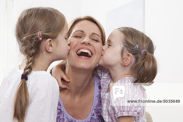 Girls (4-7) kissing on mother's cheek