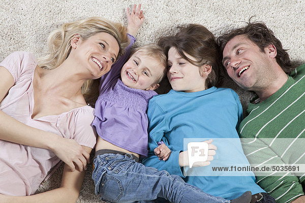 Deutschland  Bayern  München  Familie auf Teppich liegend  lächelnd
