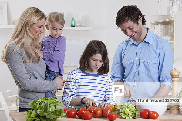 Deutschland  Bayern  München  Sohn bereitet Salat mit Vater  Mutter und Tochter neben ihnen zu.