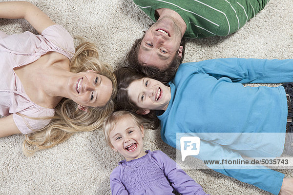 Germany  Bavaria  Munich  Family lying on carpet  laughing  portrait