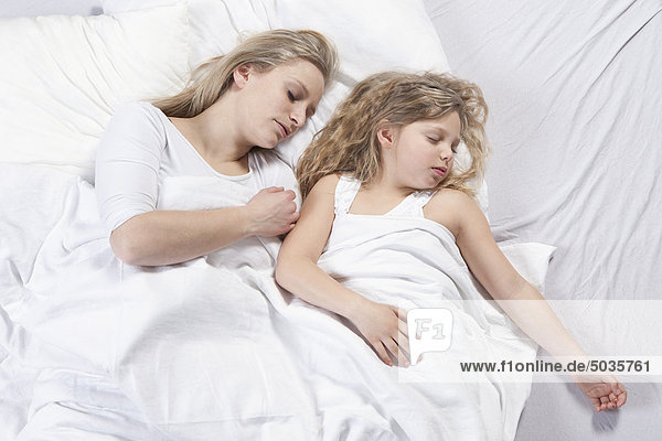 Germany  Bavaria  Munich  Mother and daughter sleeping on bed
