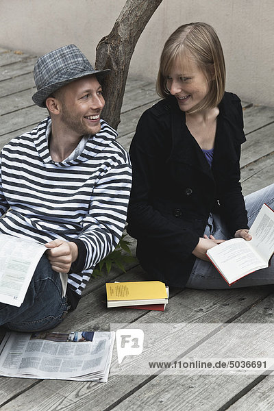 Mann liest Zeitung und Frau hält Buch