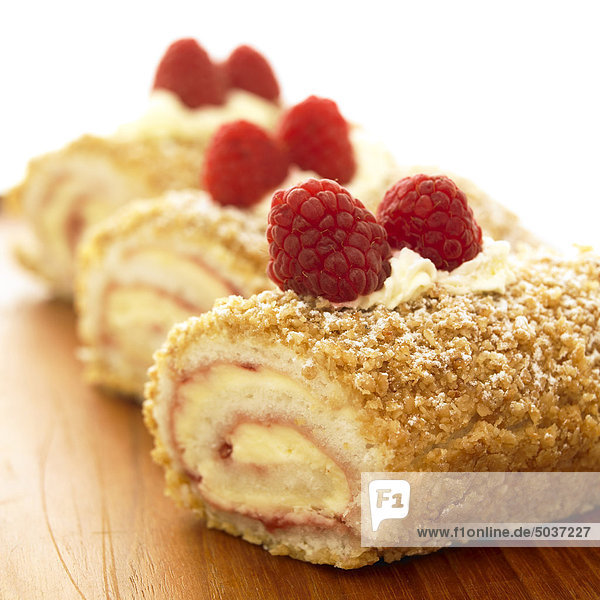 Nahaufname von drei Gelee Rollen mit Himbeeren an der Spitze