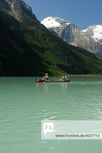 Mann und Frau paddeln Kanu in Richtung Gletscher  Moraine Lake  Lake Louise  Alberta  Kanada