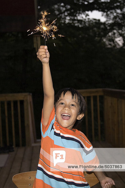 Mixed race Canadian-South Asian boy laughing and holding a sparkler  Ontario  Canada