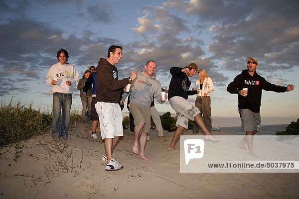 Travelers partying against a beautiful sunset over the beach  Jeffreys Bay  South Africa