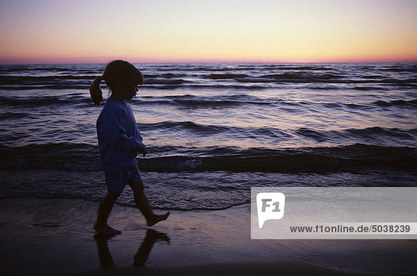 3-year-old girl walking across beach at sunset. Sauble Beach  Ontario  Canada