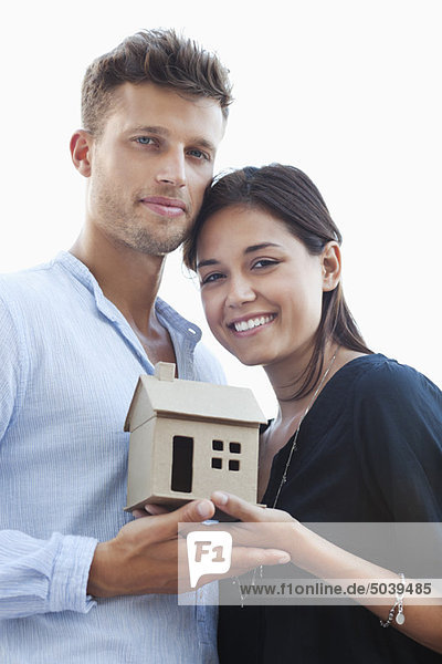 Portrait of a young couple holding small model house
