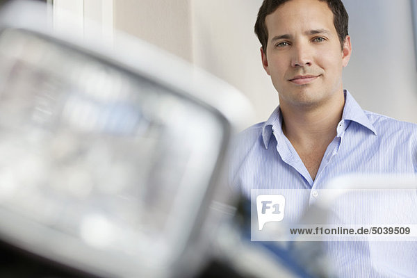 Portrait of a mid adult man standing with motorcycle in the foreground