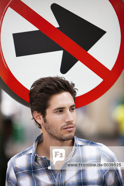 Handsome man thinking with no entry sign in the background