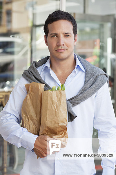 Porträt eines erwachsenen Mannes mit Papiertüten voller Gemüse