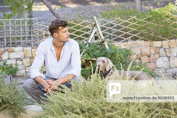Kontemplativer Mann mit Hund im Garten