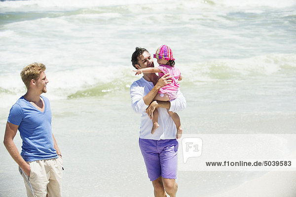 Man carrying his daughter on the beach
