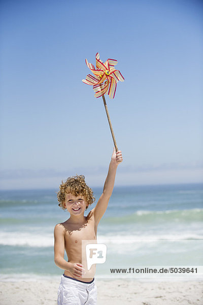Porträt eines Jungen mit einem Windrad am Strand