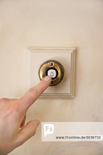 Close-up of a person's hand ringing door bell