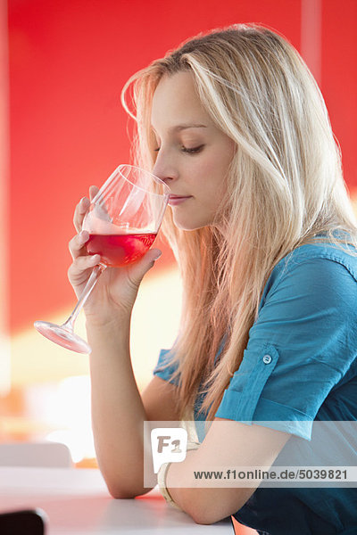 Junge Frau trinkt Rotwein in einer Bar
