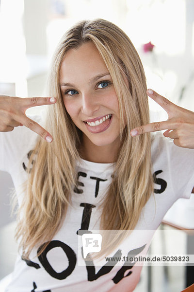 Portrait of a beautiful woman showing peace sign at a cafe