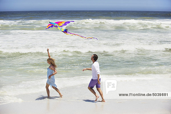 Mittleres erwachsenes Paar beim Drachenfliegen am Strand