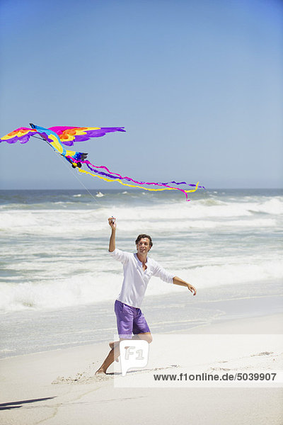 Mittlerer Erwachsener Mann beim Drachenfliegen am Strand