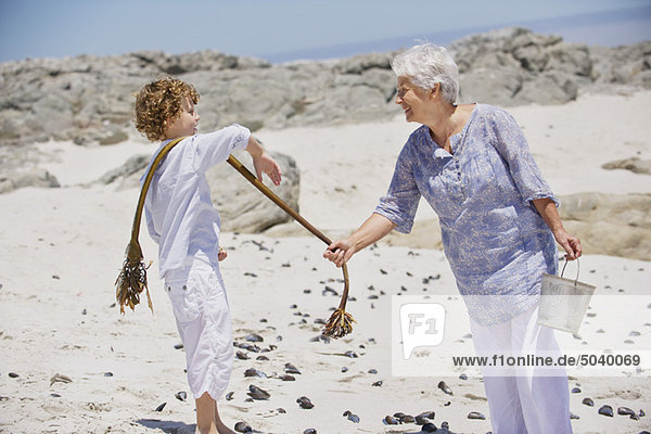 Senior woman with her grandson collecting shell on the beach