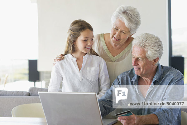 Senior man doing home shopping with a credit card with his family near him
