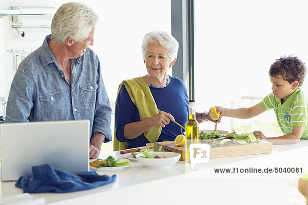 Seniorenpaar mit ihrem Enkel bei der Zubereitung des Essens in der Küche
