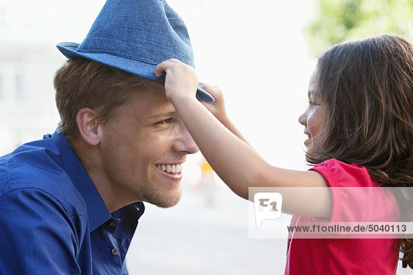 Süßes kleines Mädchen  das seinem Vater einen Hut aufsetzt.