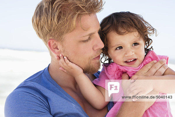 Close-up of a man carrying his daughter on the beach