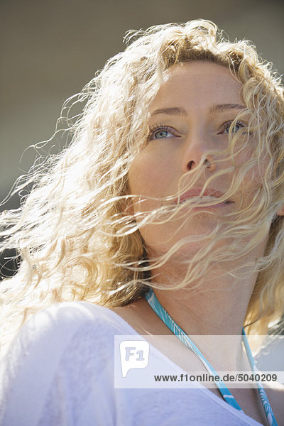 Schöne Frau schaut auf  während ihr Haar im Wind bläst.